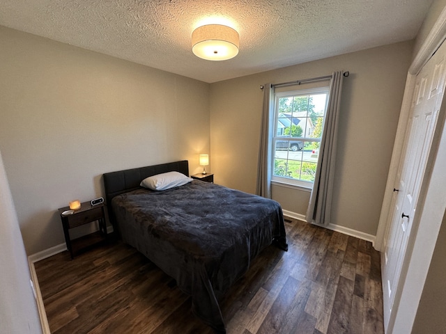 bedroom with a textured ceiling, a closet, and dark wood-type flooring