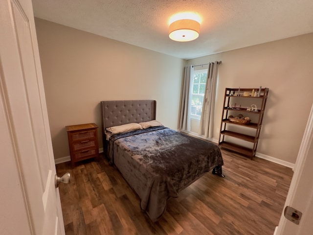 bedroom featuring a textured ceiling and dark hardwood / wood-style flooring