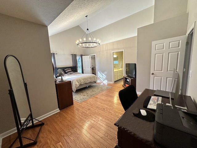 bedroom featuring an inviting chandelier, light hardwood / wood-style flooring, high vaulted ceiling, connected bathroom, and a textured ceiling