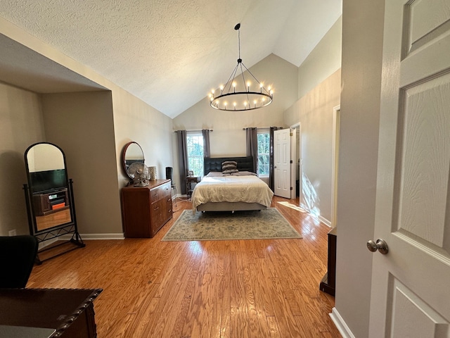 bedroom featuring a textured ceiling, high vaulted ceiling, a notable chandelier, and light hardwood / wood-style flooring