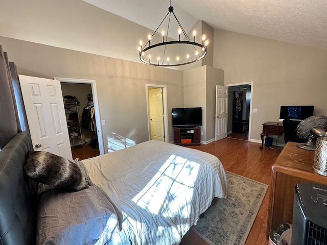 bedroom with a closet, dark hardwood / wood-style floors, an inviting chandelier, a walk in closet, and a textured ceiling