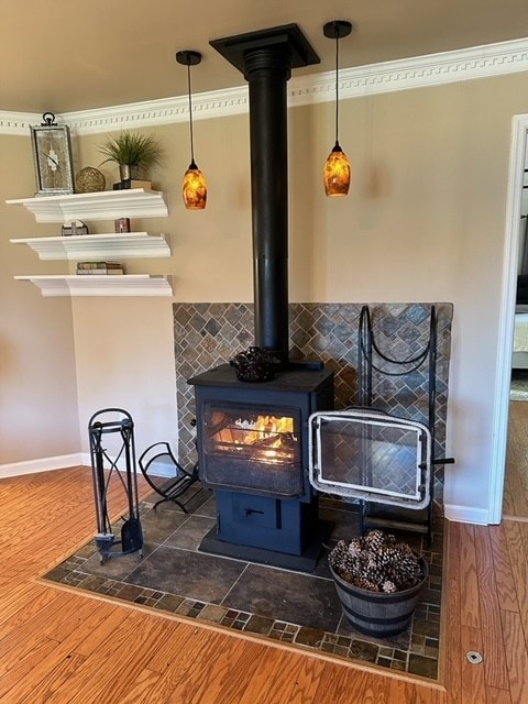 interior details with wood-type flooring, crown molding, and a wood stove