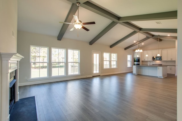 unfurnished living room featuring hardwood / wood-style floors, lofted ceiling with beams, sink, and ceiling fan with notable chandelier