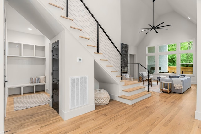 stairs with high vaulted ceiling, hardwood / wood-style flooring, and ceiling fan