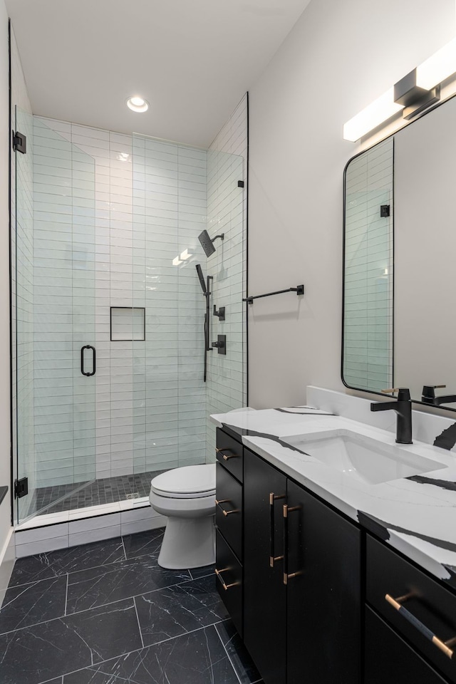 bathroom with vanity, toilet, and a shower with door