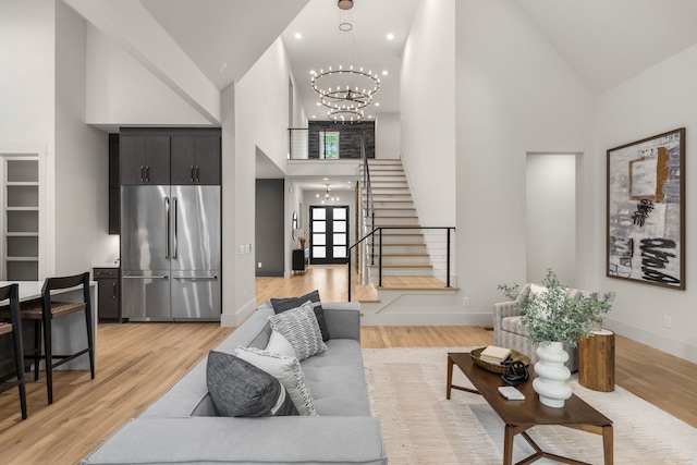 living room featuring high vaulted ceiling, a notable chandelier, and light wood-type flooring