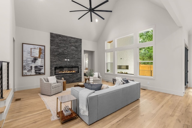 living room with a fireplace, light hardwood / wood-style floors, and high vaulted ceiling