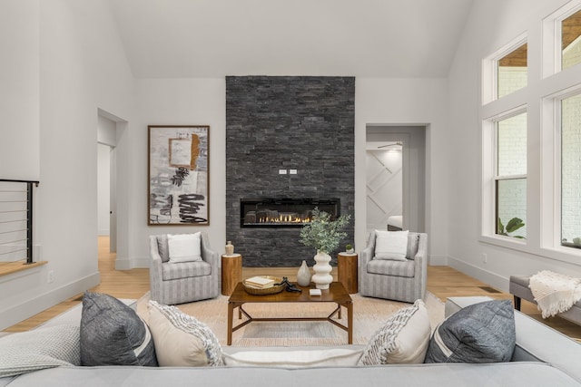 living room with light wood-type flooring, a fireplace, and vaulted ceiling