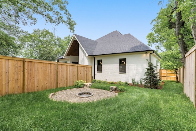 back of property featuring an outdoor fire pit and a lawn