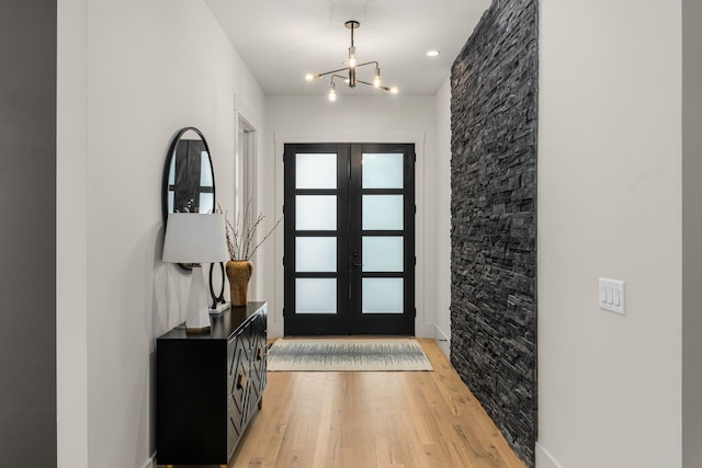 foyer entrance with french doors, a chandelier, and light hardwood / wood-style flooring