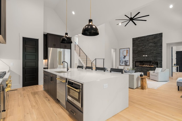 kitchen featuring a center island with sink, high vaulted ceiling, and light hardwood / wood-style floors