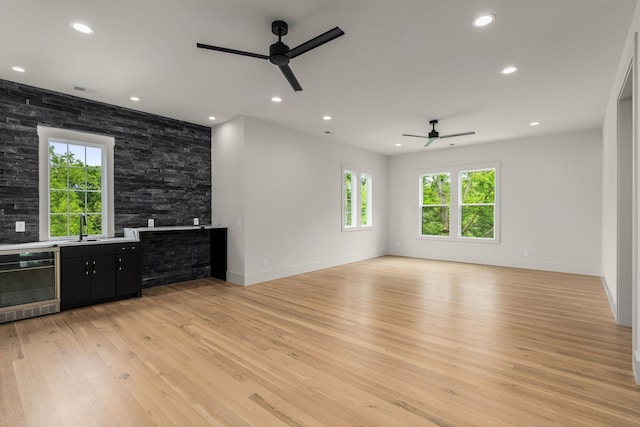 unfurnished living room featuring ceiling fan, beverage cooler, and light hardwood / wood-style flooring