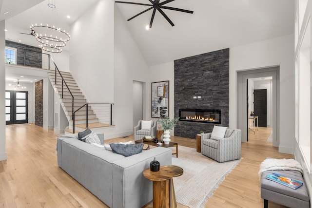 living room featuring a towering ceiling, a notable chandelier, light hardwood / wood-style floors, and a fireplace