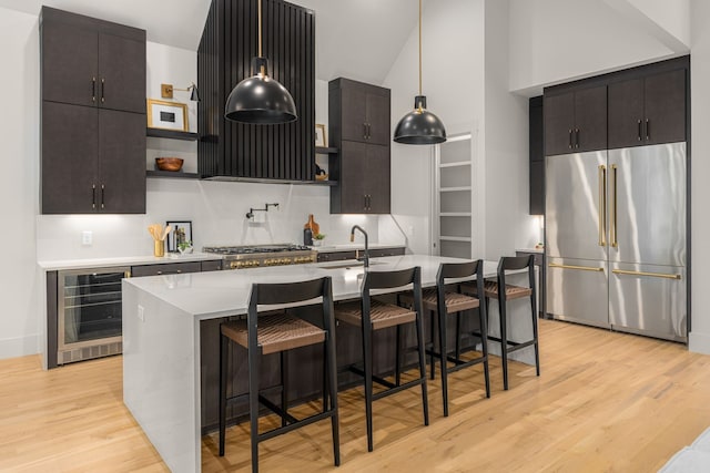 kitchen with a kitchen bar, stainless steel built in fridge, wine cooler, and light hardwood / wood-style flooring