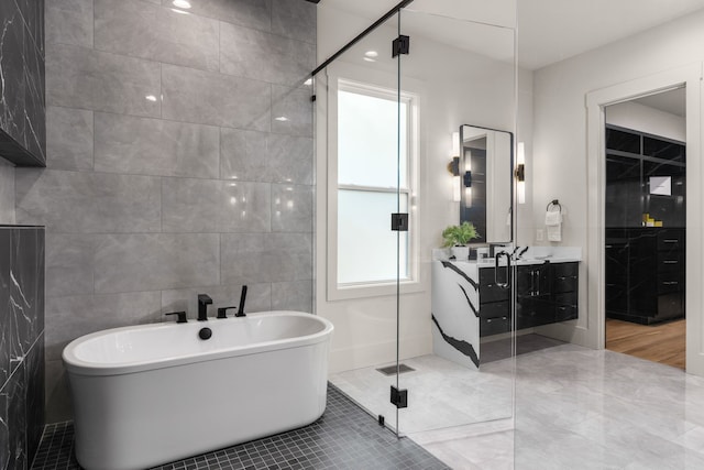 bathroom featuring separate shower and tub, vanity, and tile walls