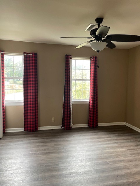 empty room with ceiling fan, hardwood / wood-style flooring, and plenty of natural light