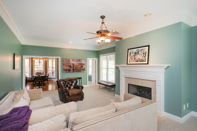 living room with ceiling fan, a tiled fireplace, ornamental molding, and light hardwood / wood-style flooring