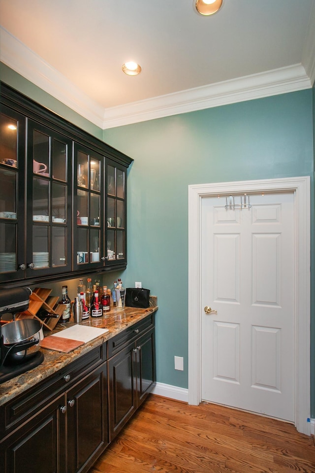 bar featuring light stone countertops, light hardwood / wood-style flooring, and crown molding