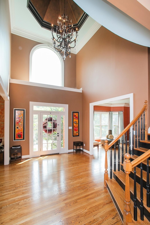 entrance foyer with crown molding, a towering ceiling, and light hardwood / wood-style flooring