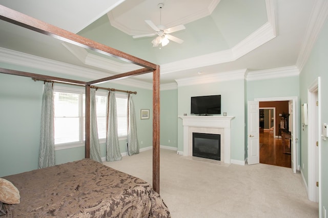 carpeted bedroom with ornamental molding, a tray ceiling, and ceiling fan