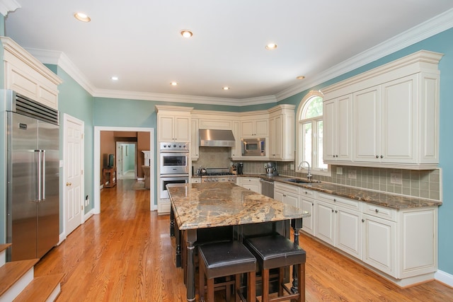 kitchen featuring sink, a kitchen island, light hardwood / wood-style flooring, exhaust hood, and built in appliances