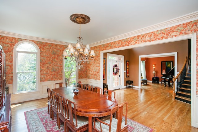 dining space with light hardwood / wood-style flooring, crown molding, and a chandelier