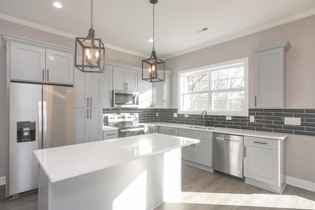 kitchen with decorative backsplash, a center island, sink, hanging light fixtures, and appliances with stainless steel finishes