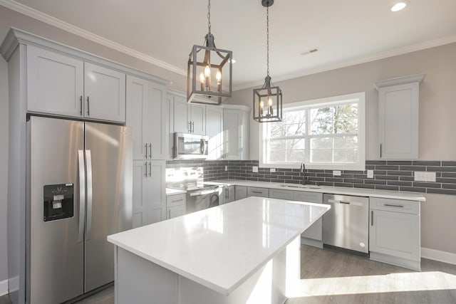 kitchen featuring a center island, wood-type flooring, pendant lighting, appliances with stainless steel finishes, and backsplash