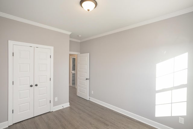 unfurnished bedroom with hardwood / wood-style flooring, crown molding, and a closet