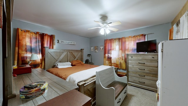 bedroom featuring light carpet, white refrigerator, and ceiling fan