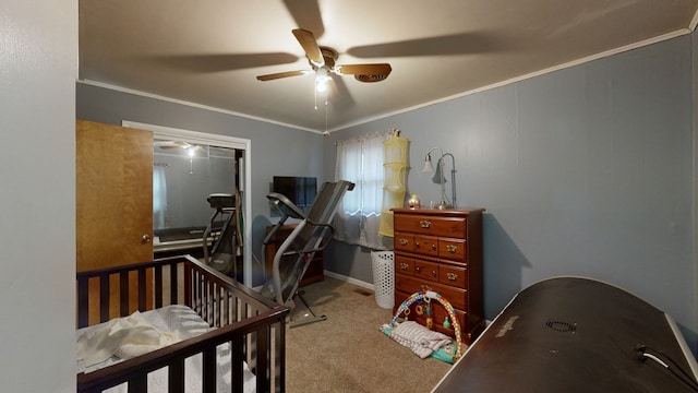 carpeted bedroom featuring ornamental molding, a crib, and ceiling fan