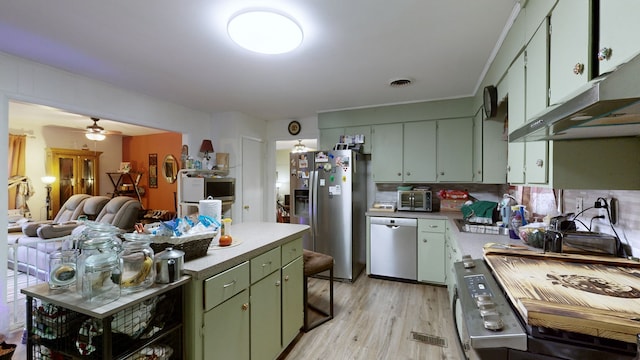 kitchen featuring decorative backsplash, green cabinets, stainless steel appliances, light hardwood / wood-style floors, and ceiling fan