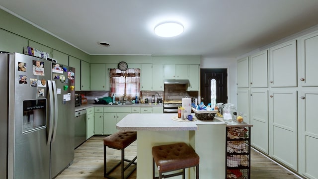 kitchen featuring tasteful backsplash, light wood-type flooring, a kitchen island, a kitchen breakfast bar, and stainless steel appliances