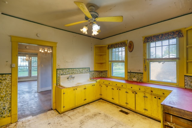 kitchen featuring light floors, a sink, visible vents, yellow cabinets, and open shelves