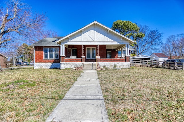 view of front of house featuring a porch, a front lawn, fence, and brick siding