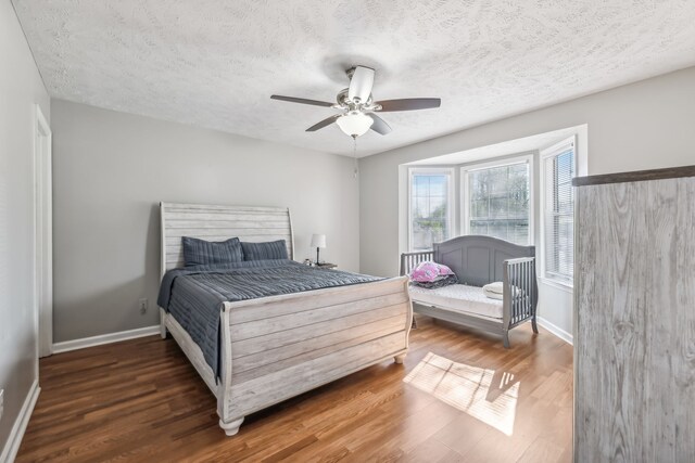 bedroom with ceiling fan, a textured ceiling, and dark wood-type flooring