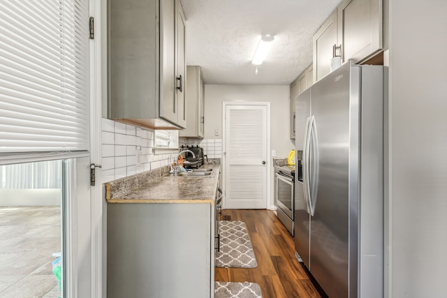 kitchen with dark hardwood / wood-style floors, tasteful backsplash, sink, appliances with stainless steel finishes, and a textured ceiling