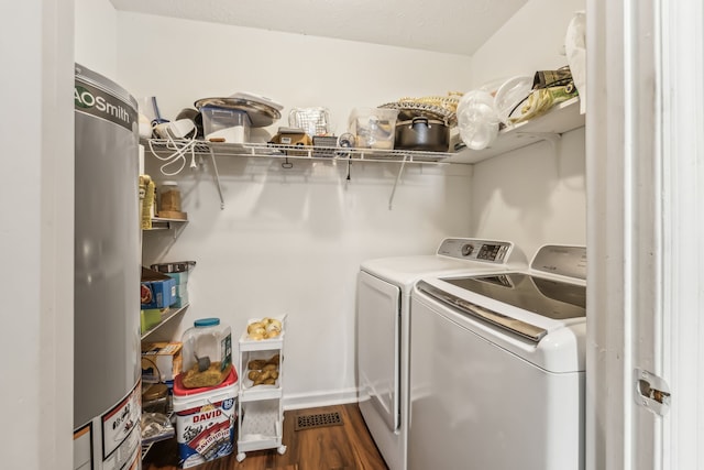 laundry area featuring gas water heater, washer and clothes dryer, and dark hardwood / wood-style flooring