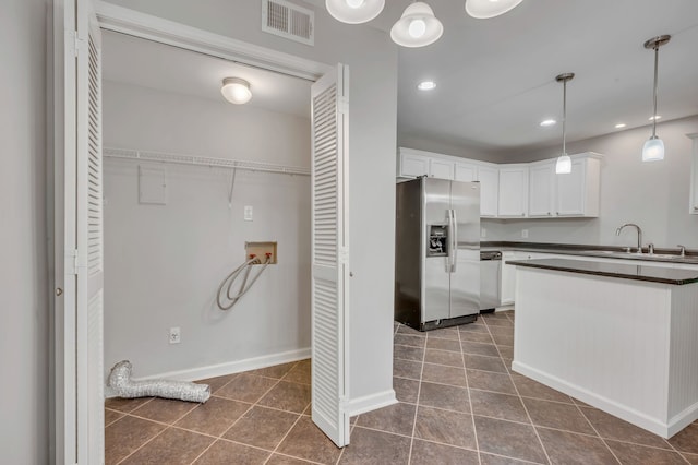 kitchen featuring white cabinets, dark tile patterned flooring, sink, decorative light fixtures, and stainless steel appliances