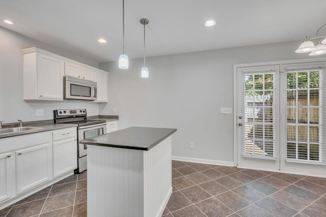 kitchen with pendant lighting, sink, white cabinetry, appliances with stainless steel finishes, and a center island