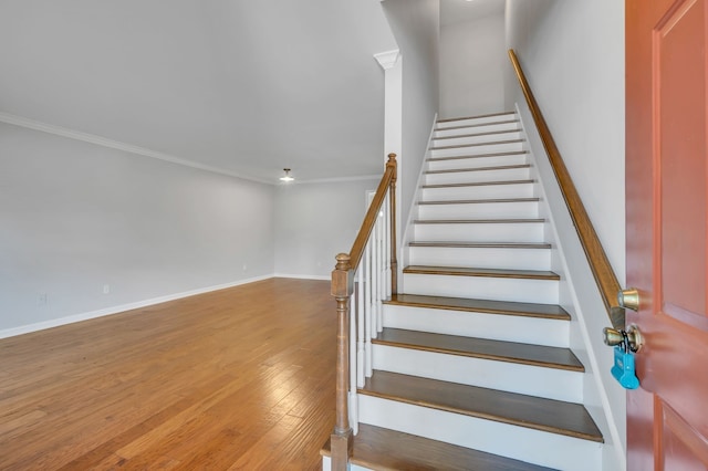 staircase with wood-type flooring and crown molding