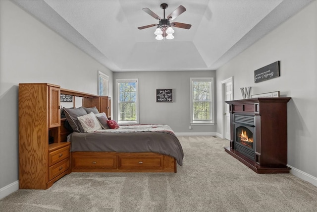 carpeted bedroom featuring a tray ceiling and ceiling fan