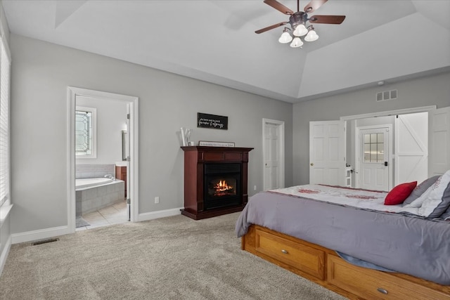 bedroom featuring ceiling fan, light carpet, connected bathroom, and vaulted ceiling