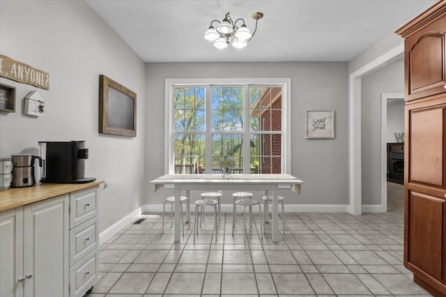 tiled dining room with a textured ceiling and a notable chandelier