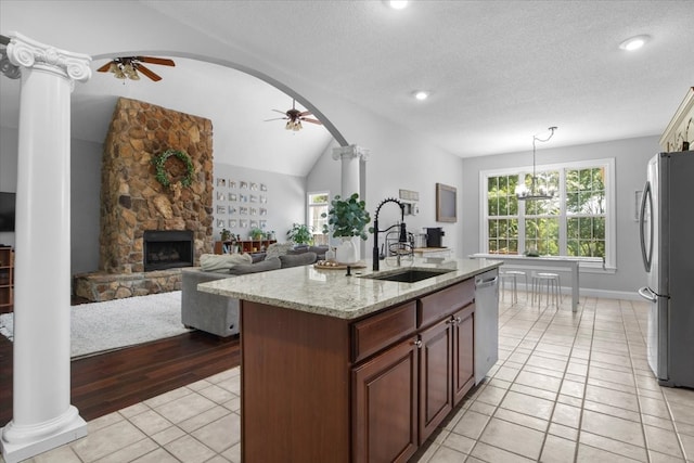 kitchen featuring stainless steel appliances, sink, light hardwood / wood-style floors, lofted ceiling, and an island with sink