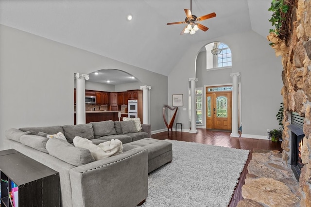 living room featuring a stone fireplace, ceiling fan, high vaulted ceiling, and dark hardwood / wood-style floors