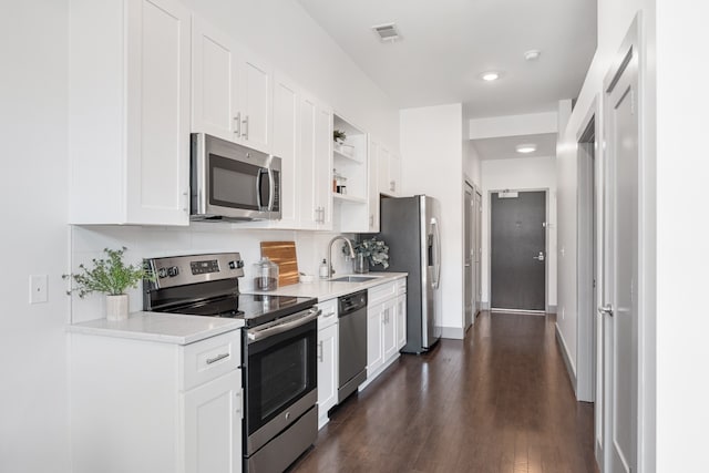 kitchen with decorative backsplash, white cabinets, dark wood-type flooring, sink, and appliances with stainless steel finishes