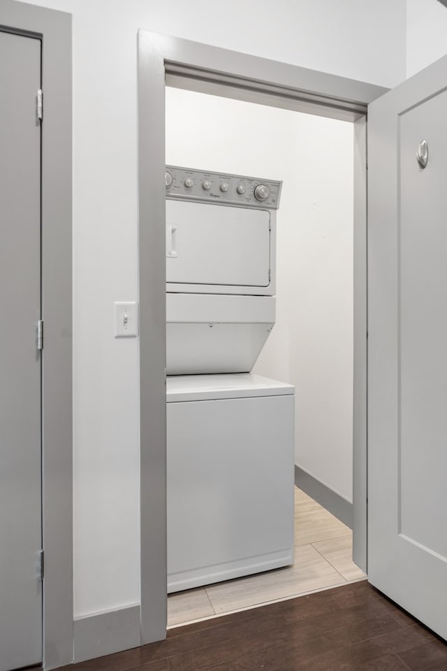 clothes washing area with hardwood / wood-style flooring and stacked washing maching and dryer