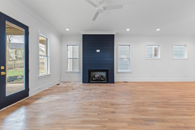 unfurnished living room featuring a fireplace, light hardwood / wood-style flooring, ceiling fan, and crown molding