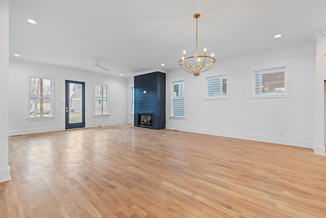 unfurnished living room featuring ornamental molding, ceiling fan with notable chandelier, a large fireplace, and light hardwood / wood-style floors